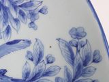 a blue and white plate with a bird and flowers on it