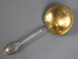a gold spoon with a spoon handle on a gray surface