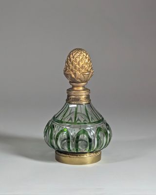 flacon de parfum en verre vert et doré, orné d'un ananas sur le bouchon