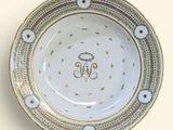 a white plate with gold trim and a monogram on it