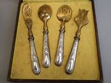 three spoons and a spoon rest in a case on a table