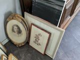 beaucoup de photos encadrées posées par terre à côté d'une commode