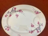 une assiette blanche ornée de fleurs roses, posée à côté d'une tasse et d'une soucoupe