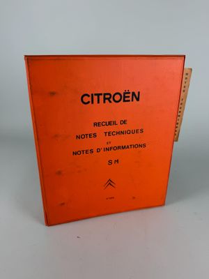 un livre orange posé sur une table près d'un mur blanc