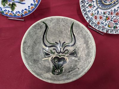 un bol orné d'une tête de taureau, posé sur une table