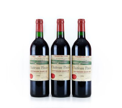 trois bouteilles de vin rouge posées l'une à côté de l'autre sur une surface blanche