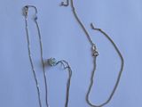 deux colliers en argent et une chaîne en argent sur fond blanc
