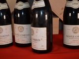 four bottles of wine are lined up on a red table