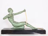 statue d'une femme assise sur un socle noir, tenant un ruban jaune