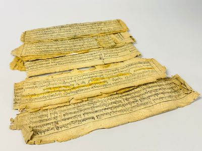 trois morceaux de parchemin portant des inscriptions, posés sur une table