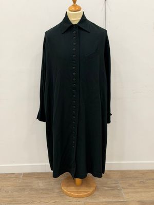 a black shirt on a mannequin stand in front of a white wall