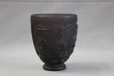 un vase brun orné d'un motif sur une surface blanche