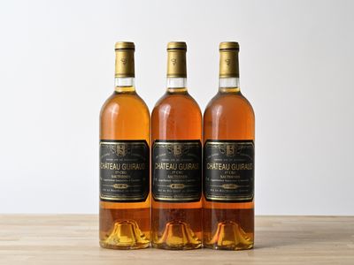 three bottles of wine sitting on top of a wooden table next to each other