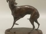 statue en bronze représentant un lévrier en pleine course, posée sur un socle en bois