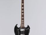 a black electric guitar hanging from a white wall