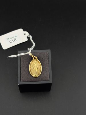 une petite médaille en or posée sur une boîte noire, accompagnée d'une étiquette