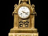 a gold clock that is sitting on a black surface