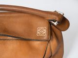 brown leather handbag with a gold logo on the front