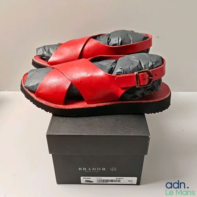 une paire de sandales rouges et noires posée sur une boîte noire
