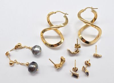 plusieurs paires de boucles d'oreilles et un collier posés sur une surface blanche