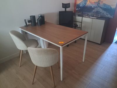 une table et deux chaises dans une pièce où est accroché un tableau au mur