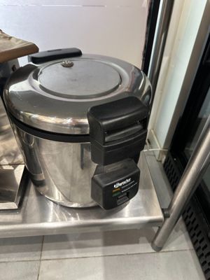 un cuiseur à riz argenté et noir posé sur une étagère en métal