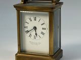 une petite horloge en laiton avec des chiffres romains sur le cadran