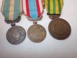 three medals are displayed on a white surface with a red, white, and blue ribbon