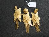 three gold tone earrings with tassels and a tag on a black surface