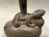 a statue of a frog sitting on top of a bowl
