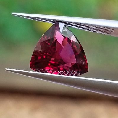 a red diamond that is being held up by a pair of pliers