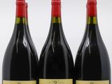 trois bouteilles de vin rouge sont alignées sur une surface blanche