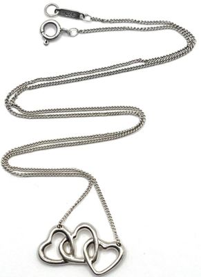 deux pendentifs en forme de cœur sont suspendus à une chaîne sur un fond blanc