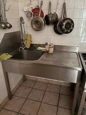 une cuisine équipée d'un évier, d'une cuisinière et de casseroles accrochées au mur