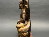 a statue of a woman sitting on top of a wooden block