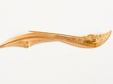 a gold plated hair clip on a white surface