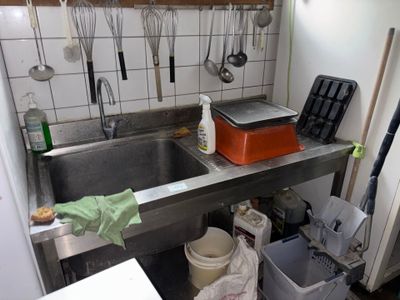 une cuisine équipée d'un évier et de nombreux ustensiles accrochés au mur