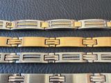 three men ' s stainless steel bracelets on a black leather surface