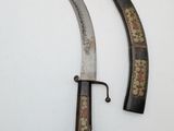 pair of antique chinese swords on display on a white surface