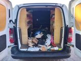the back of a van with the door open filled with junk