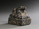 une image représentant une statue en pierre d'une grenouille assise sur un rocher
