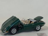 a green toy car that is sitting on a white surface