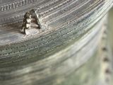 a close up of a metal bell with a skull on it