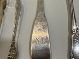 a lot of silver spoons and spoons hanging on the wall