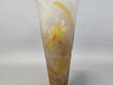 a vase with a yellow flower on it on a white surface