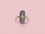 une bague ancienne sertie d'un diamant, sur fond rose