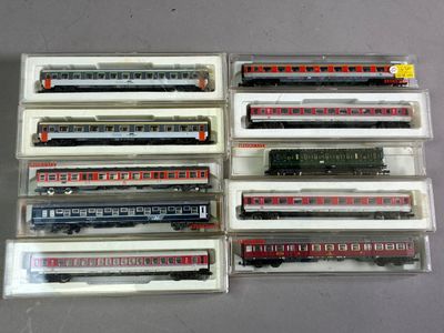 six trains miniatures dans des boîtes en plastique, posés sur une table
