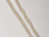 a close up of a necklace on a table with a white background