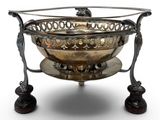 a large silver plated bowl on a stand with a wooden base