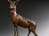 sculpture en bronze représentant un cerf debout sur un rocher, sur fond gris